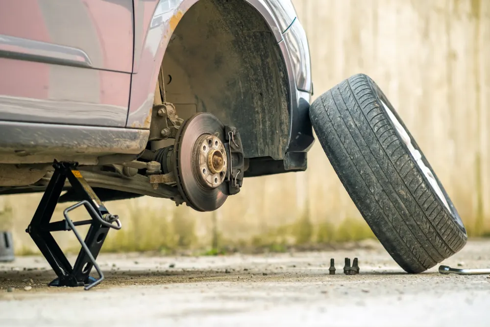 Have you bought a faulty car on finance? Featured Image. Image shows a close up of a car lifted on a jack.