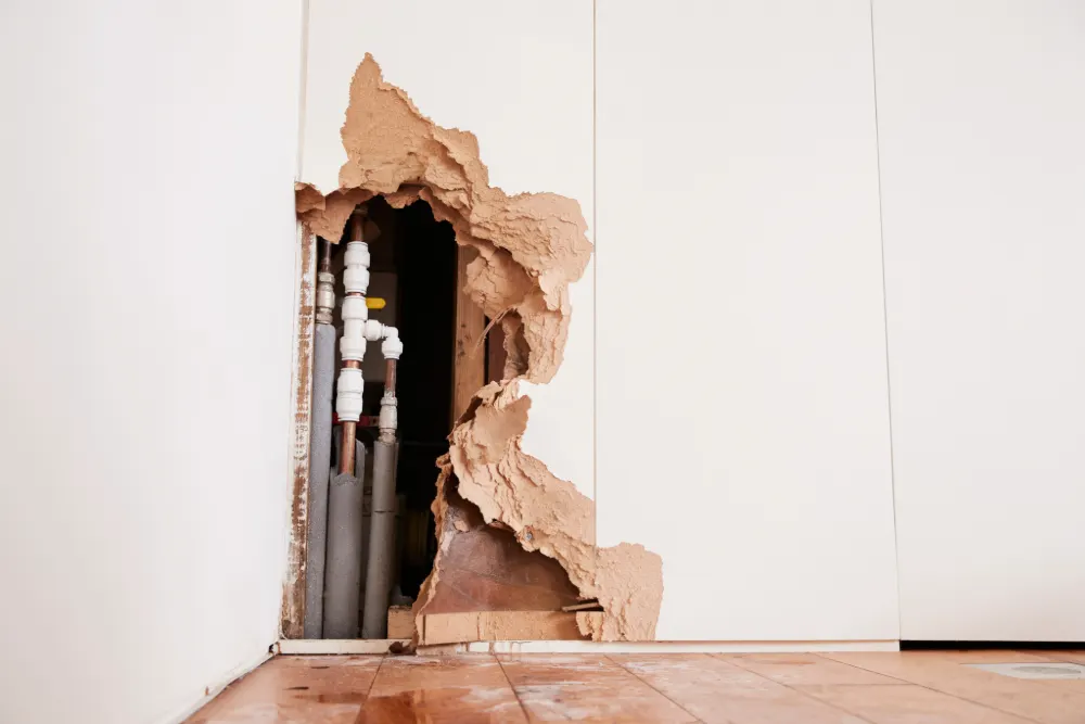 Why your housing disrepair claim is important featured image. Image shows a damaged wall exposing a burst water pipe.