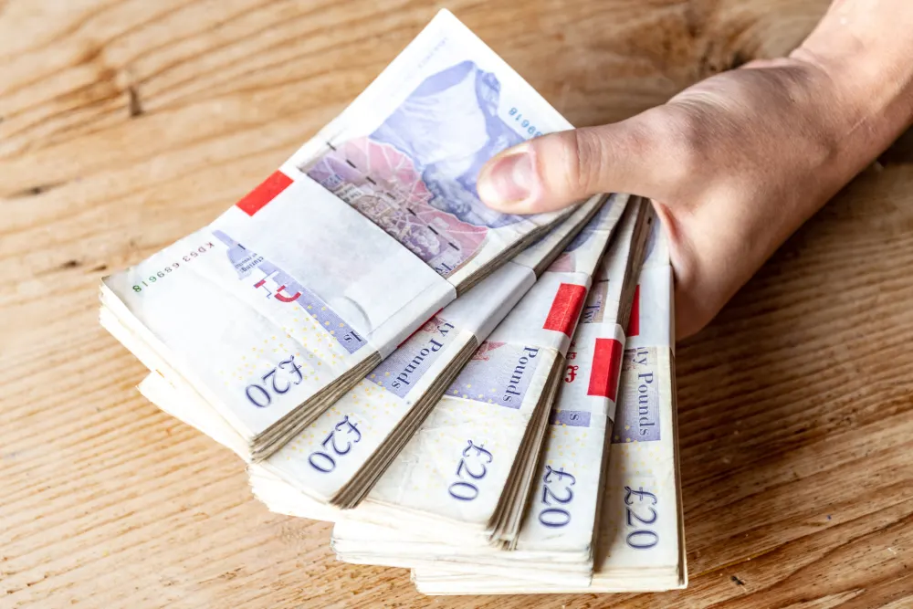 Irresponsible Lending featured image. Hand holding five wads of £20 notes.