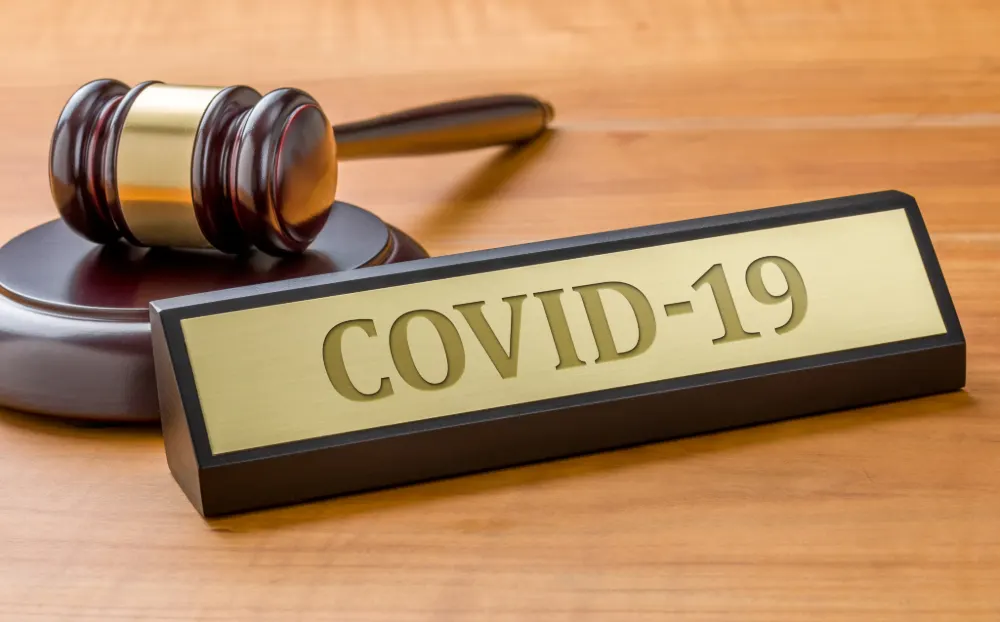 Businesses featured image. Wooden gavel and a plaque saying 'Covid-19'