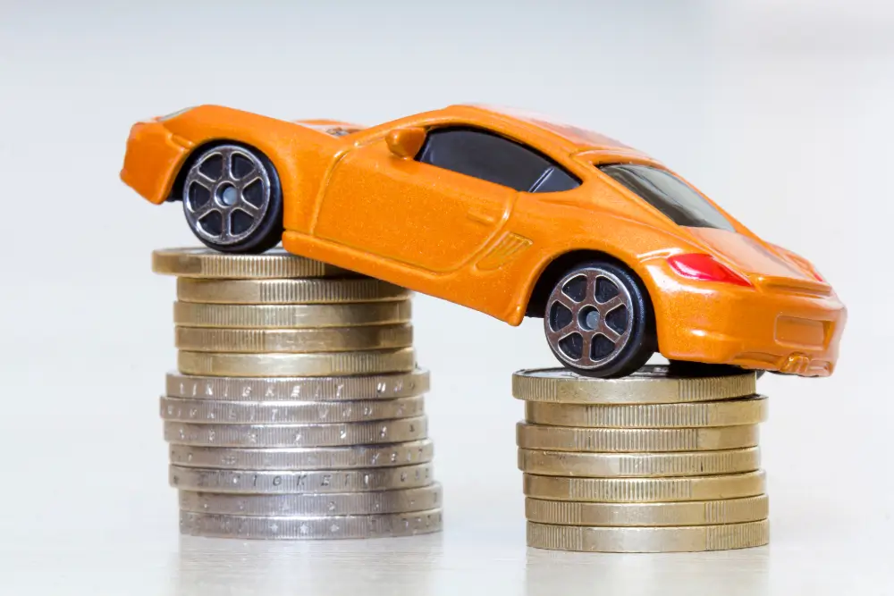 What Is Mis-sold Car Finance? Featured Image. Orange toy car on top of two stacks of coins.